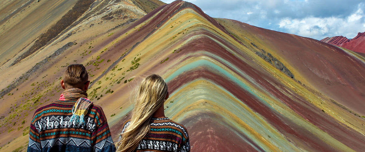 Backpacker couple wearing alpaca sweaters at Vinicunca Rainbow Mountain in Cusco, Peru
